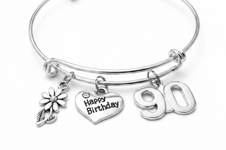 Silver expandable charm bangle bracelet with daisy flower charm, Happy Birthday heart charm with crystal accent, and bold 90 number charm, displayed on white background — 90th birthday gift for women by Jules Obsession