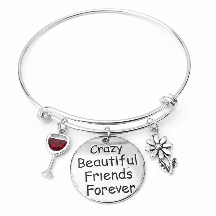 Silver adjustable bangle bracelet with three charms: a red wine glass charm, a round engraved disc reading Crazy Beautiful Friends Forever, and a silver daisy flower charm, displayed on a white studio background