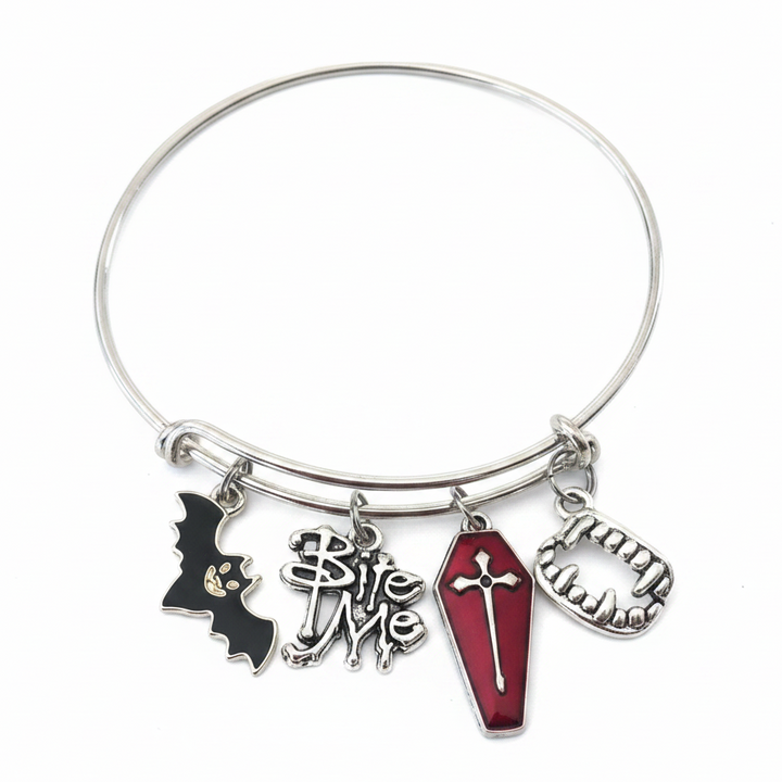 Silver expandable bangle bracelet with four Halloween vampire charms including a black enamel bat, silver Bite Me text charm, red enamel coffin with cross, and silver vampire fangs, photographed on a white studio background