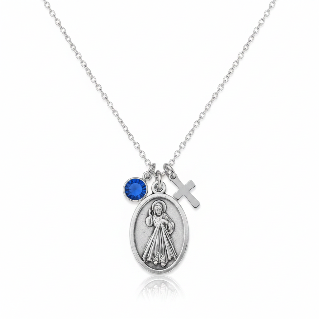 Silver Divine Mercy medal necklace with blue crystal birthstone and cross charm on a warm white background