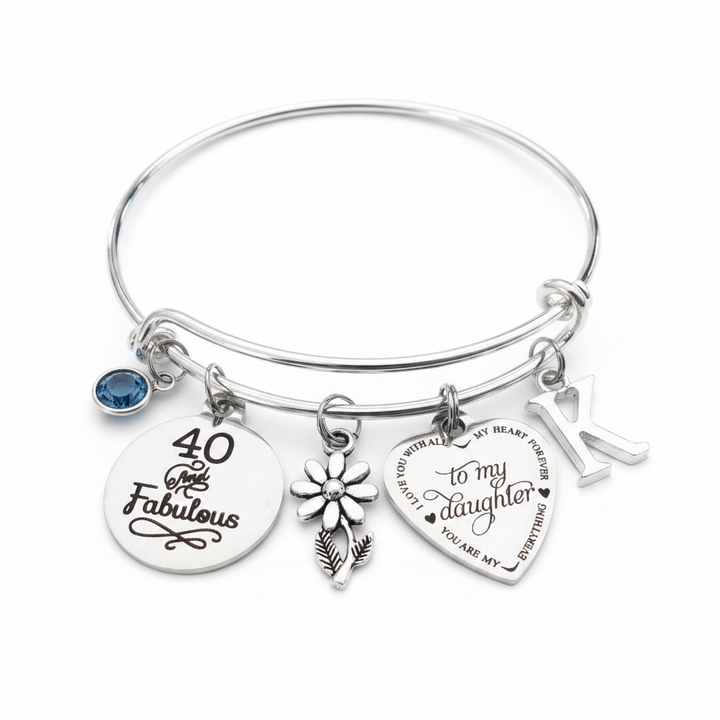 Silver expandable charm bangle bracelet with 40 and Fabulous disc, to my daughter heart charm, daisy flower charm, birthstone crystal, and initial letter charm on white background