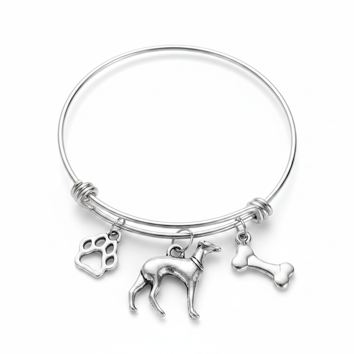 Silver expandable bangle bracelet with three antique silver dog-themed charms: a paw print charm, a greyhound dog figurine charm, and a bone charm, displayed on a white studio background