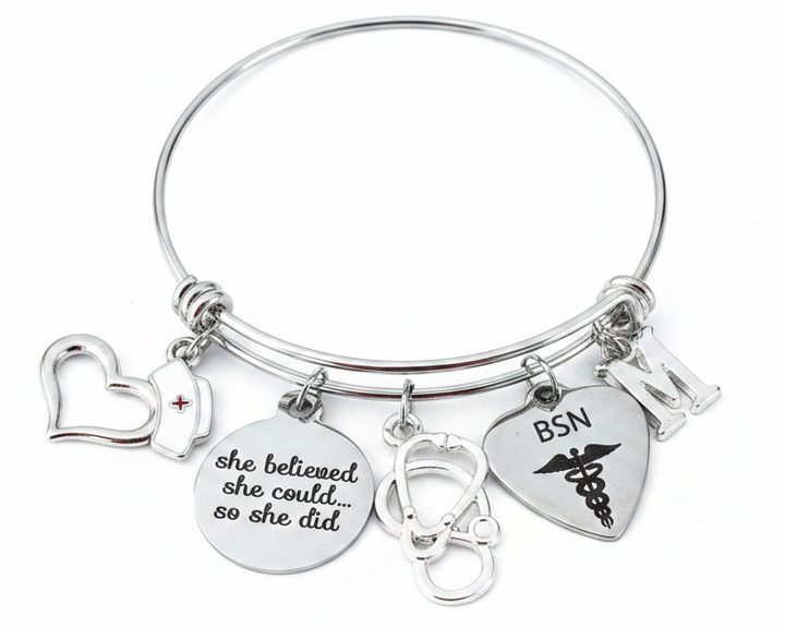 Silver expandable stainless steel bangle bracelet with BSN nurse-themed charms including BSN engraved heart with caduceus, stethoscope, nurse cap, open heart, inspirational disc charm reading she believed she could so she did, Bachelor of Science in Nursing