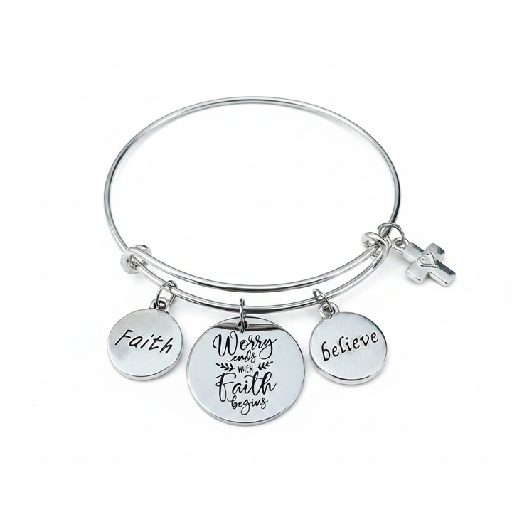Professional studio photo of silver faith charm bangle bracelet with engraved Faith, Believe, Worry Ends When Faith Begins discs and cross charm on white background — Jules Obsession