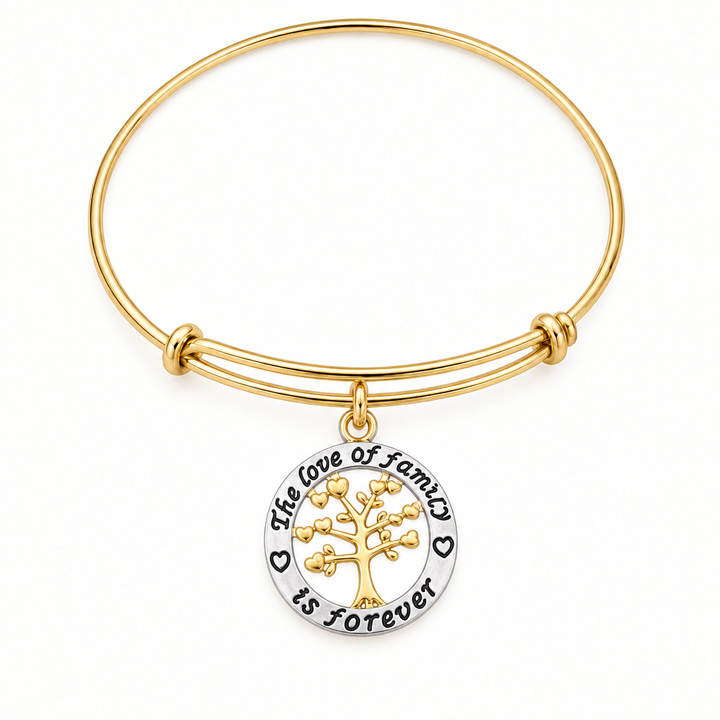 Gold bangle bracelet with a round pendant engraved "The love of family is forever" featuring a gold tree of life with heart leaves, shown on a warm-white studio background