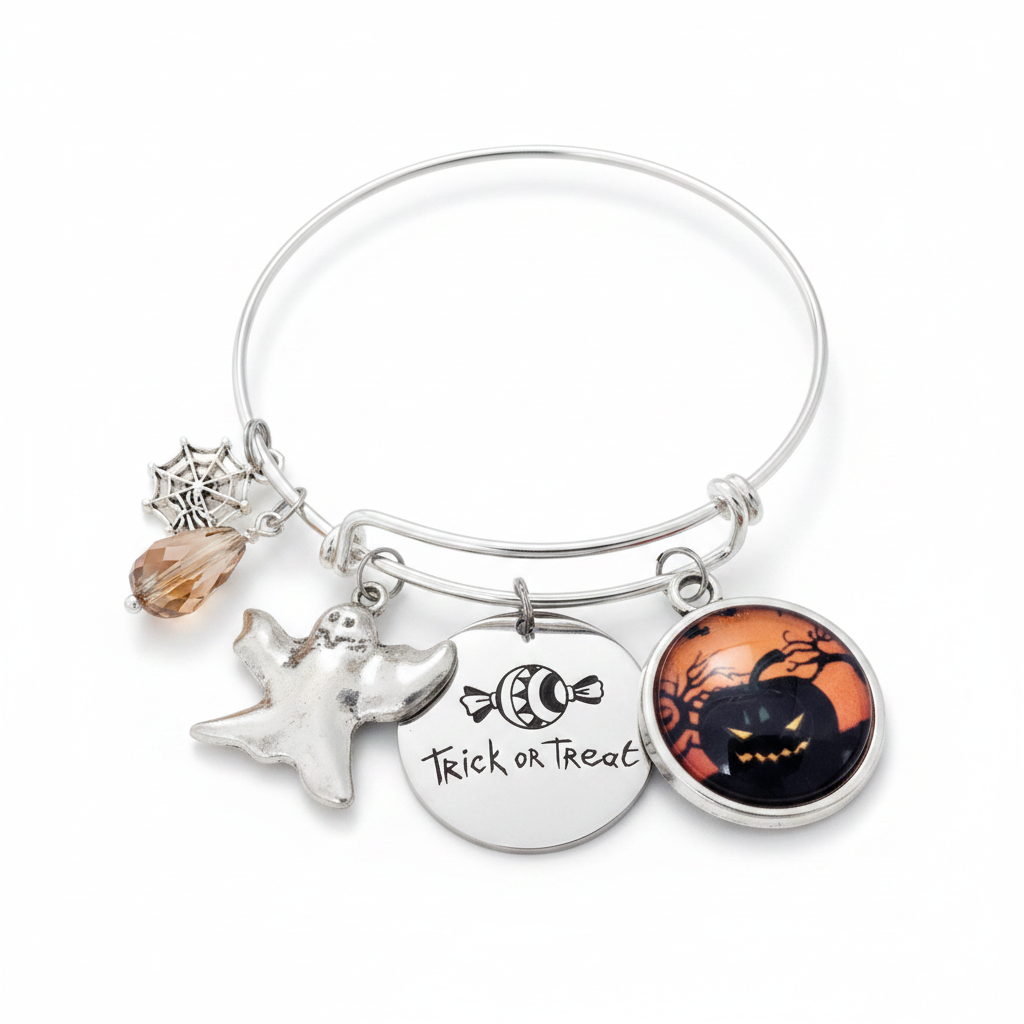 Silver expandable Halloween charm bangle bracelet on white background featuring spider web charm, amber crystal teardrop bead, ghost charm, Trick or Treat engraved disc charm, and jack-o-lantern glass cabochon pendant