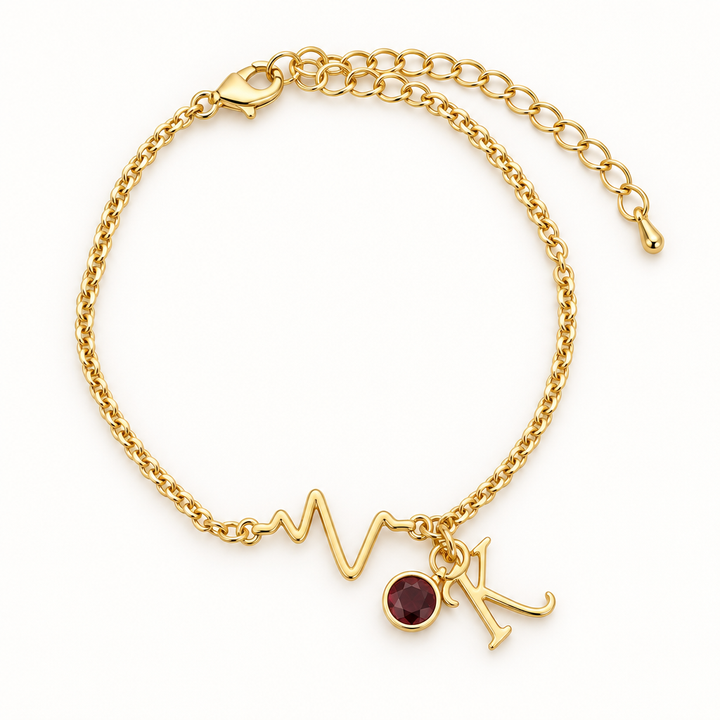 Gold-tone chain bracelet with a heartbeat detail, burgundy stone charm, and K letter charm.