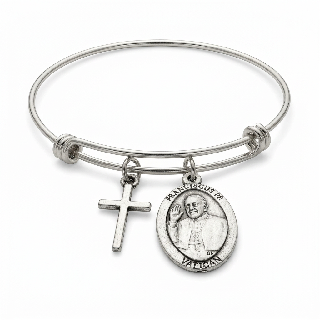 Expandable stainless steel bangle with attached cross charm and oval Pope Francis portrait medal on a white studio background.