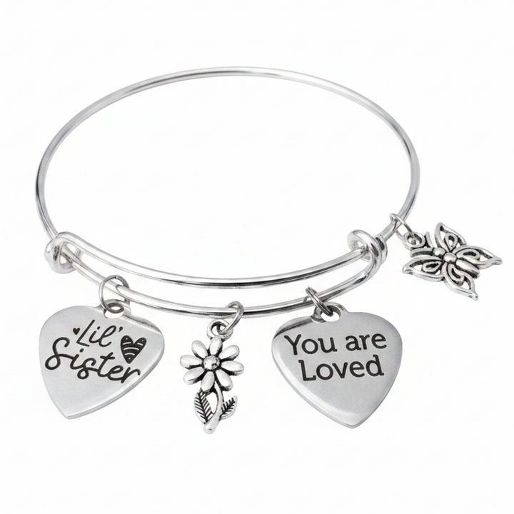 Silver expandable charm bangle bracelet featuring Lil Sister and You Are Loved heart charms, daisy flower charm, and butterfly charm on white studio background