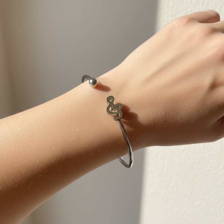 Woman wearing polished silver treble clef open cuff bangle bracelet with ball end – stainless steel music bracelet by Jules Obsession