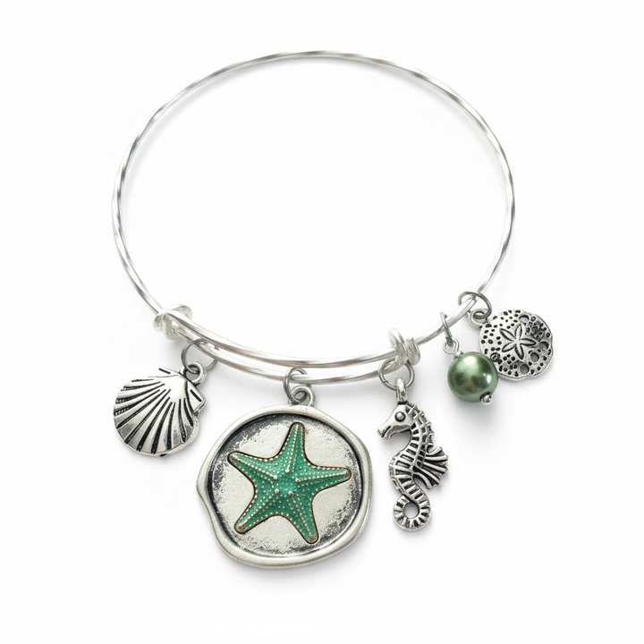 Nautical Charm Bangle Bracelet with starfish, seahorse, sea shell, sand dollar and pearl charms on twisted matte silver expandable bangle by Jules Obsession