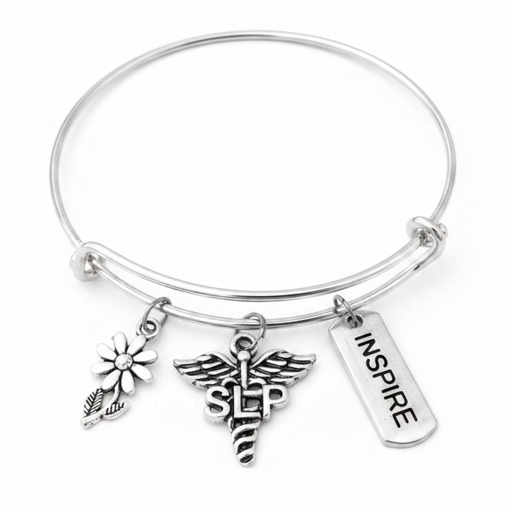 Silver expandable bangle bracelet with SLP caduceus charm, daisy flower charm, and Inspire tag charm on white studio background