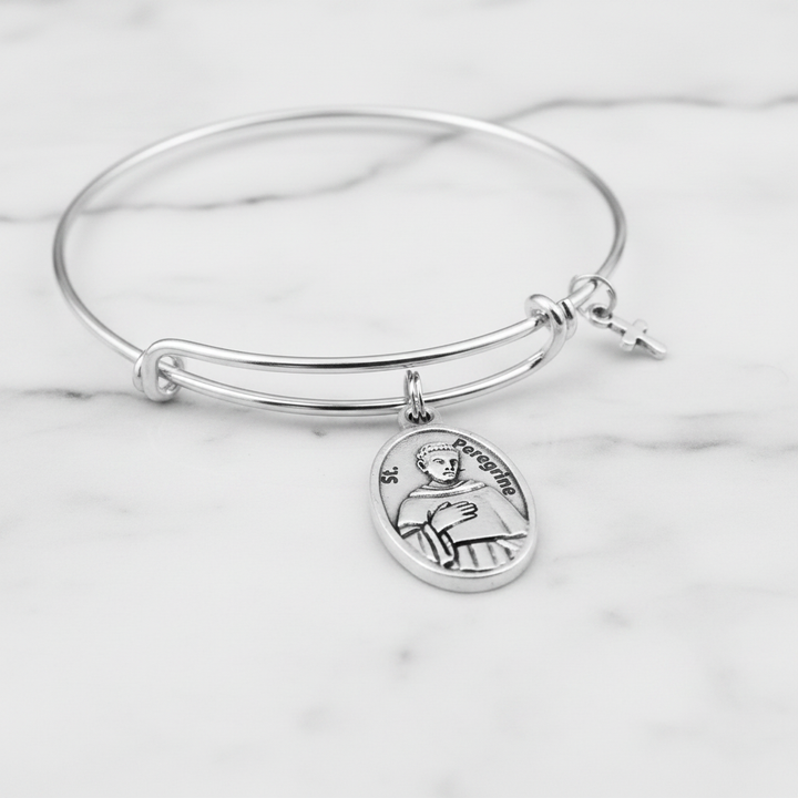 Close-up of St. Peregrine antique silver oval relic medal charm on expandable wire bangle bracelet