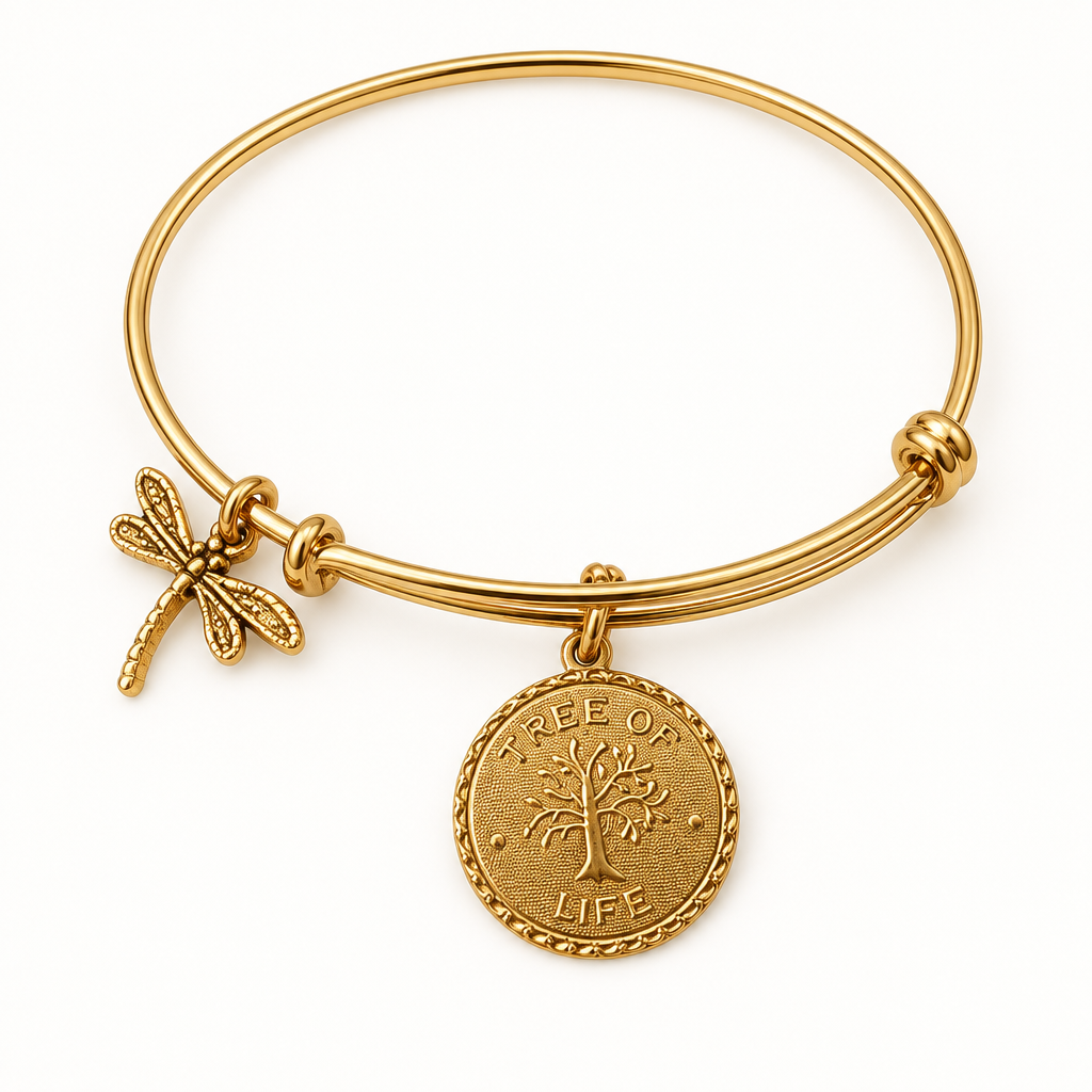 Gold bangle bracelet with a dragonfly charm and a round Tree of Life coin charm, shown on a clean warm-white studio background
