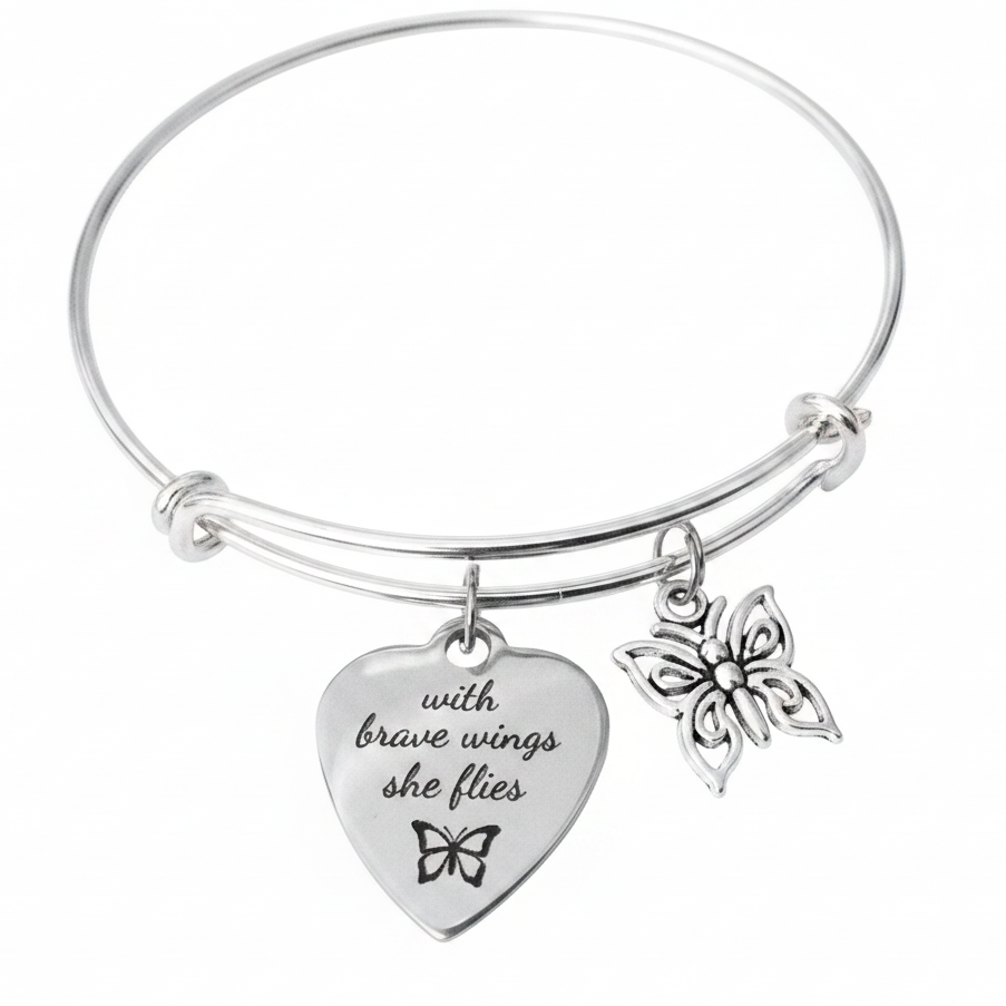 Silver expandable bangle bracelet with engraved heart charm reading 'with brave wings she flies' with butterfly silhouette and ornate open-work butterfly charm on white background