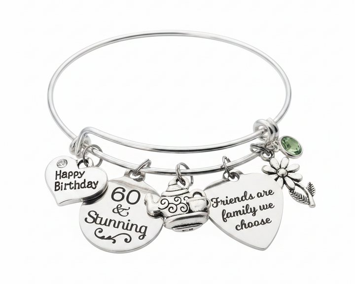 Silver expandable bangle bracelet with Happy Birthday heart charm, 60 and Stunning disc charm, teapot charm, Friends are family we choose heart charm, daisy flower charm, and green birthstone crystal bead on white background - Jules Obsession