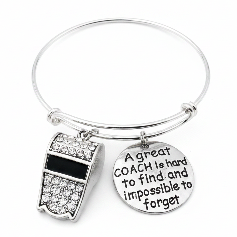 Silver expandable bangle bracelet with crystal rhinestone whistle charm and engraved round disc reading A great coach is hard to find and impossible to forget, on white studio background