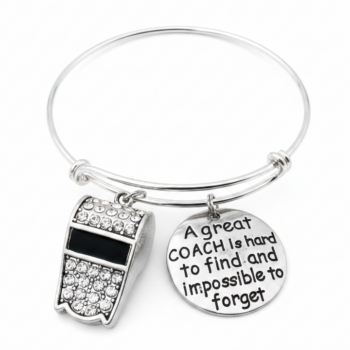 Silver expandable bangle bracelet with crystal rhinestone whistle charm and engraved round disc reading A great coach is hard to find and impossible to forget, on white studio background