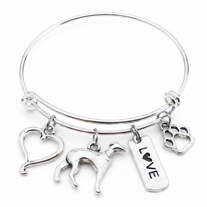 Silver expandable bangle bracelet with four antique silver charms: an open heart, a greyhound dog silhouette, a LOVE tag with heart, and a paw print, displayed on a white studio background