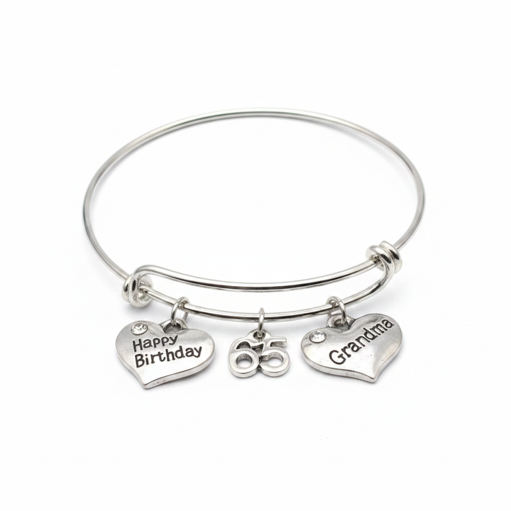 Professional studio photo of silver charm bangle bracelet with Happy Birthday heart, 65 number, and Grandma heart charms on white background