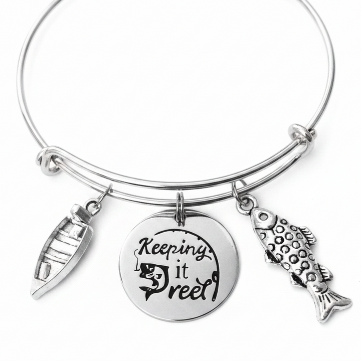 Silver expandable bangle bracelet with Keeping it Reel engraved disc charm, fishing lure charm, and detailed fish charm on white background – Jules Obsession fishing gift jewelry for women