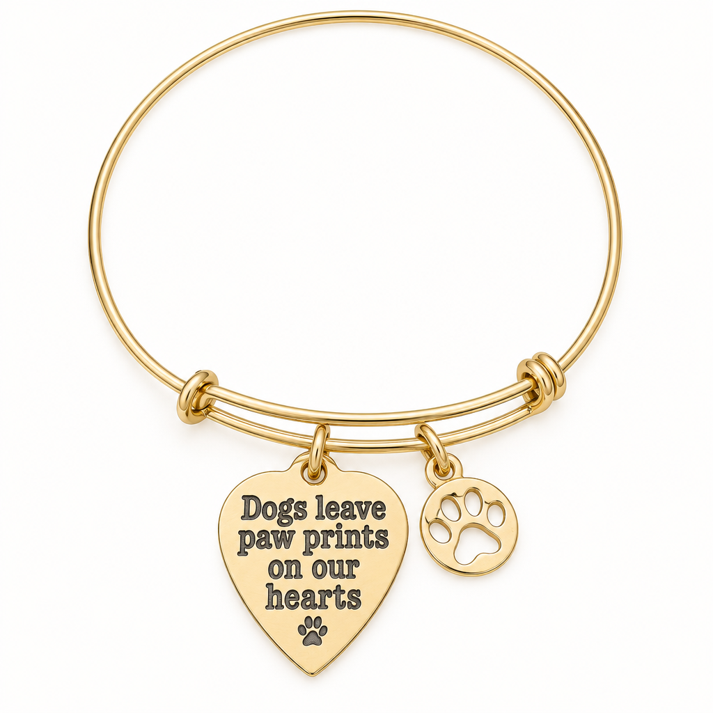 Gold bangle bracelet with a heart charm engraved Dogs leave paw prints on our hearts and a round paw print charm, shown on a warm-white studio background