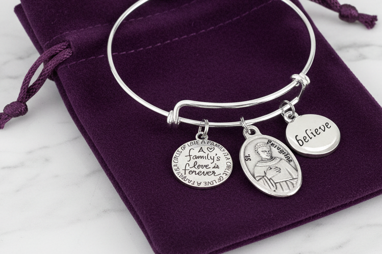 St. Peregrine charm bracelet displayed in velvet jewelry pouch — gift-ready Catholic bracelet for cancer patients