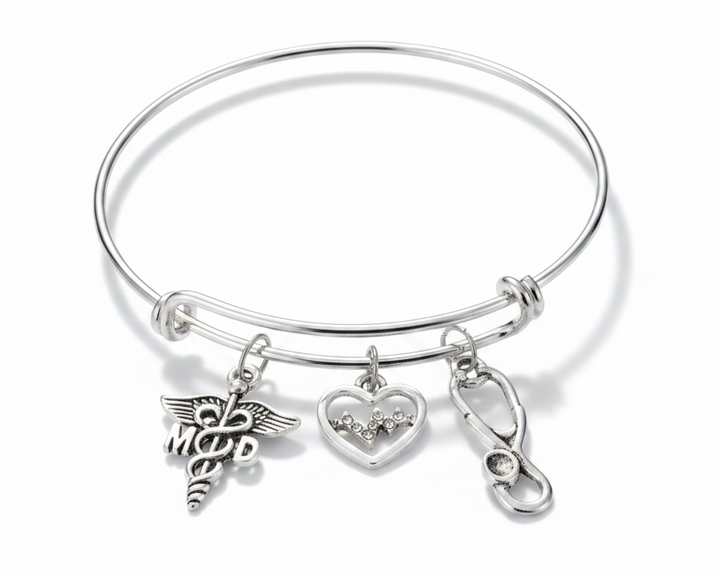 Silver expandable bangle bracelet with MD caduceus charm, crystal EKG heart charm, and stethoscope charm on white background — physician gift jewelry