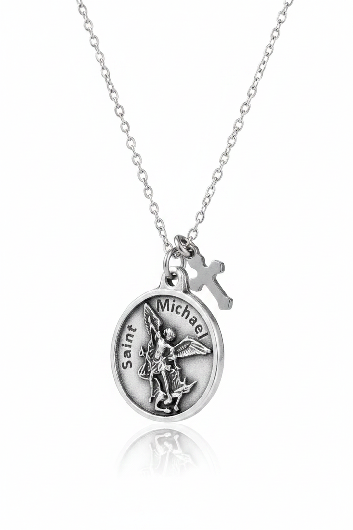 Silver Saint Michael the Archangel round medal necklace with small cross charm on delicate cable chain, on white studio background