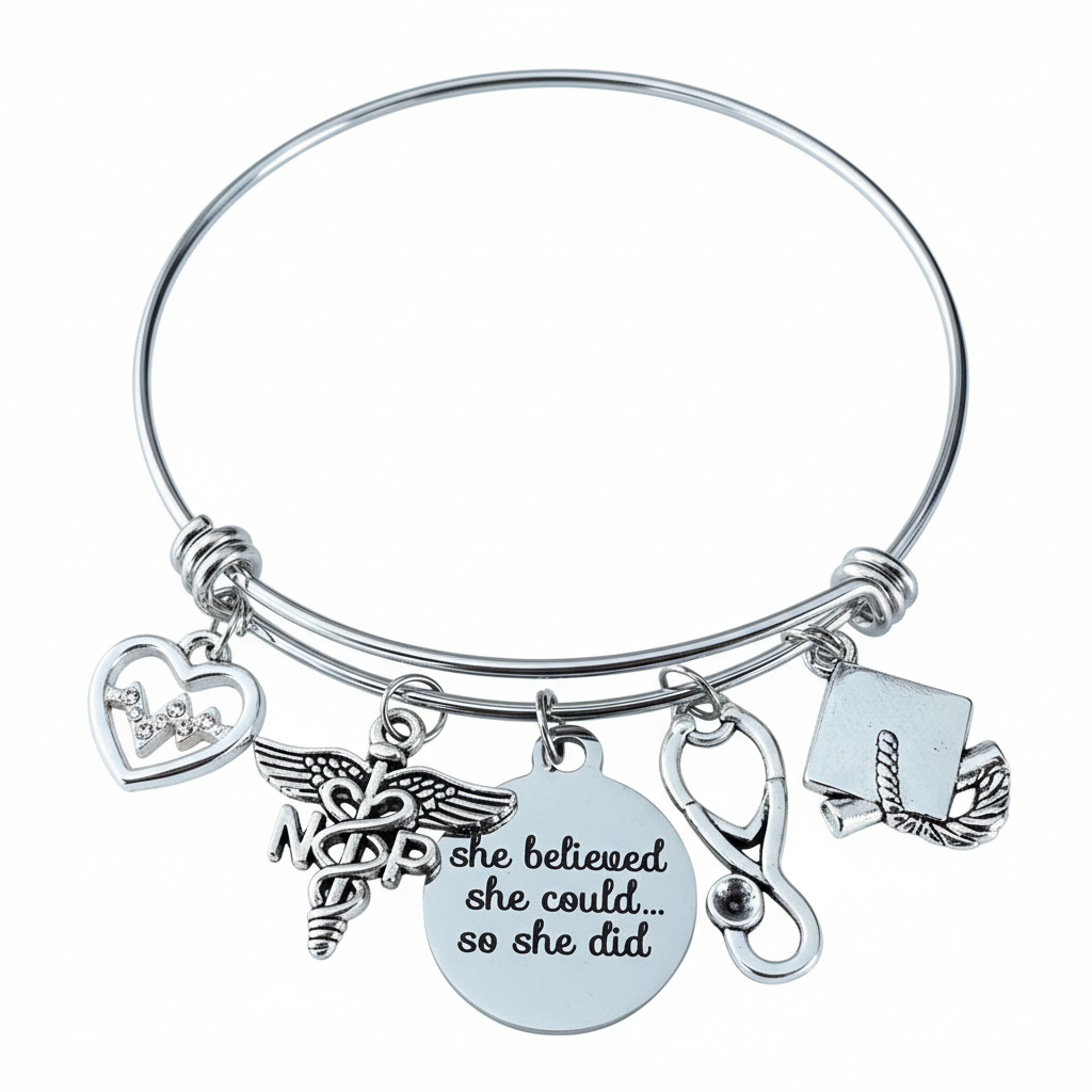 Silver expandable bangle bracelet with NP caduceus nurse practitioner charm, EKG heartbeat heart charm, "She Believed She Could So She Did" engraved disc, stethoscope charm, and graduation cap charm, on a white studio background