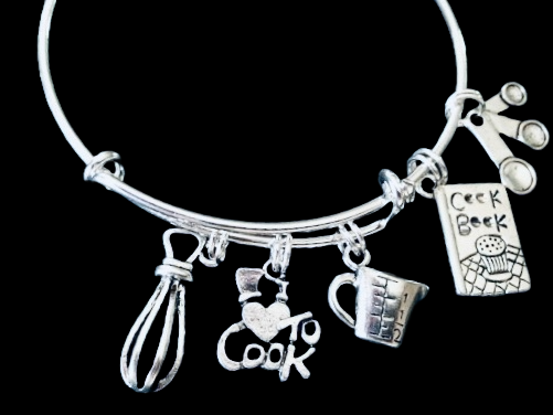 A silver adjustable bangle bracelet with charms including a chef's hat, a whisk, a heart-shaped pendant, and a measuring cup, 