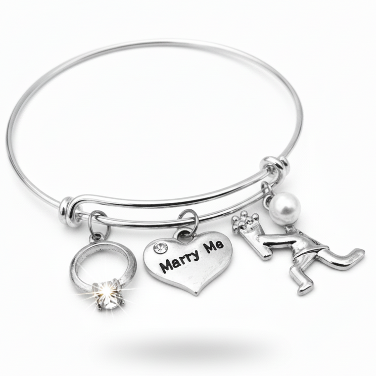 Silver bracelet with 'Marry Me' heart charm and ring charm on a white background