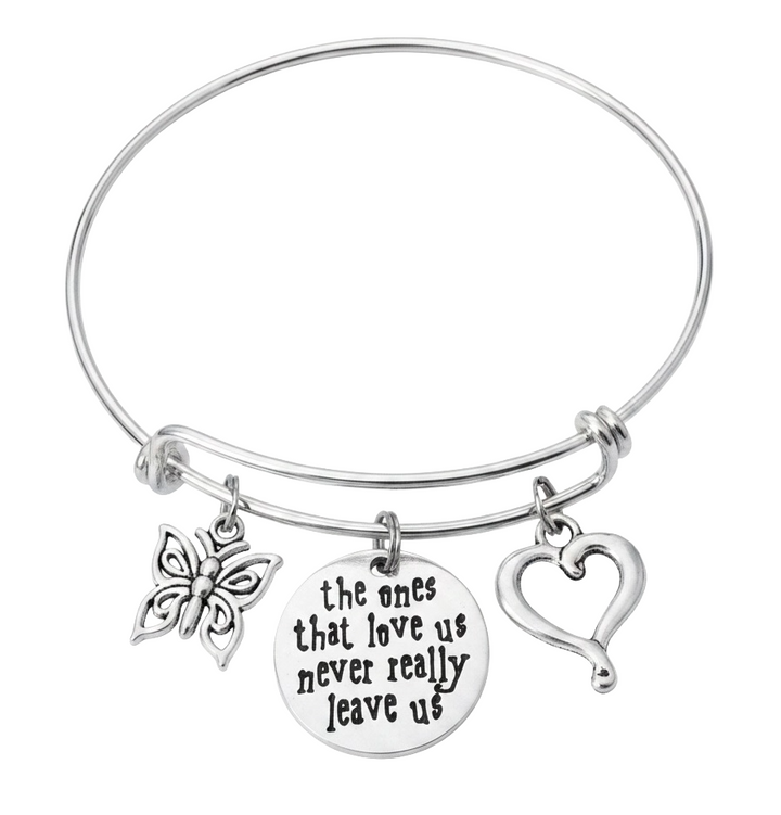 A silver-toned expandable wire bangle bracelet with three charms: a butterfly, a round engraved disc reading &