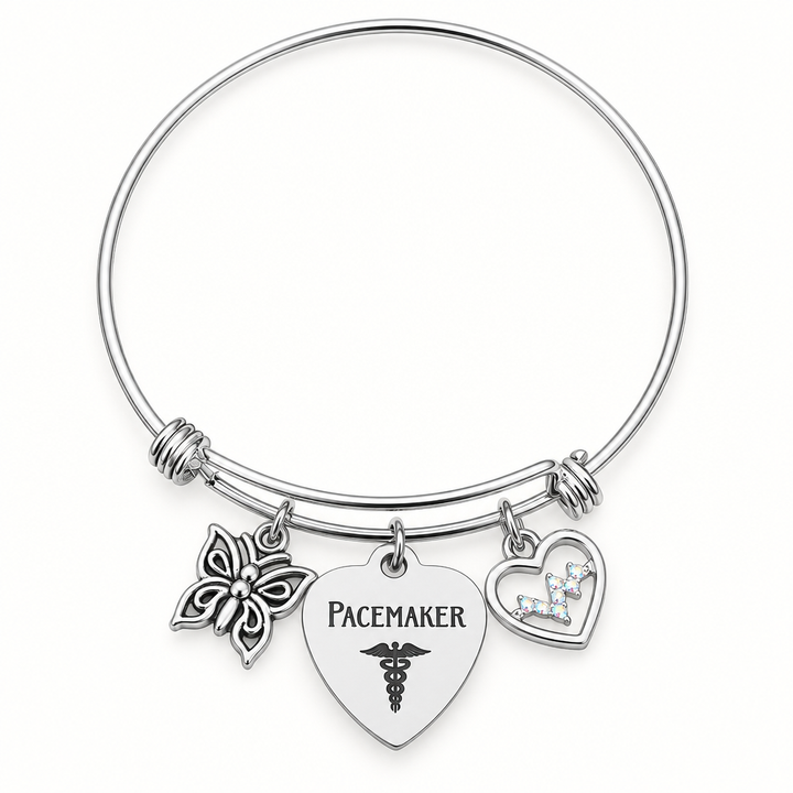 Silver-tone expandable bangle bracelet with a butterfly charm, a heart-shaped “Pacemaker” tag, and an open heart charm with a small butterfly.