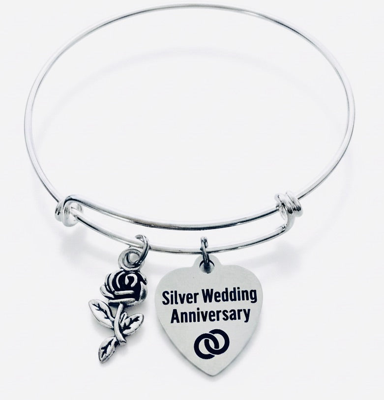 Silver expandable bangle bracelet with two charms: a detailed silver rose with stem and leaves, and a Silver Wedding Anniversary heart charm with interlocking rings — 25th anniversary gift for wife"