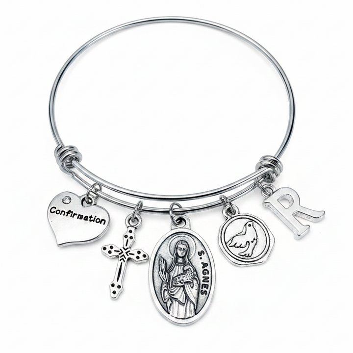 Confirmation charm bangle bracelet featuring Saint Agnes saint medal, decorative cross charm, Confirmation heart, Holy Spirit dove medallion, and personalized silver initial charm