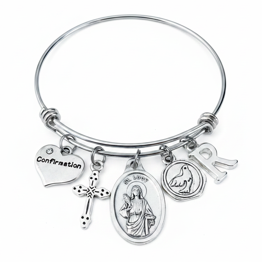 Confirmation charm bangle bracelet featuring Saint Lucy saint medal, decorative cross charm, Confirmation heart, Holy Spirit dove medallion, and personalized silver initial charm