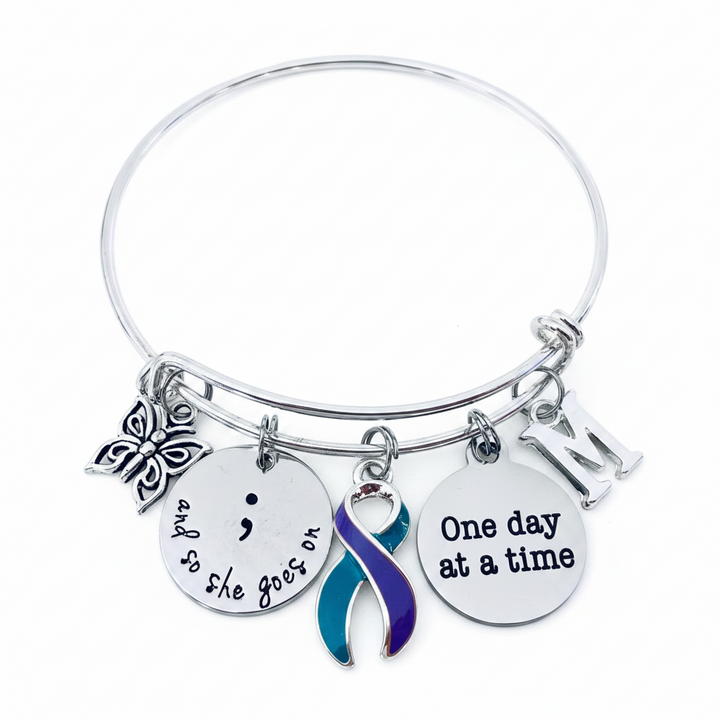 Suicide Prevention Awareness Bracelet with semicolon, teal and purple ribbon, butterfly, and "One day at a time" charm on adjustable silver bangle — gift-ready jewelry for mental health advocates and survivors