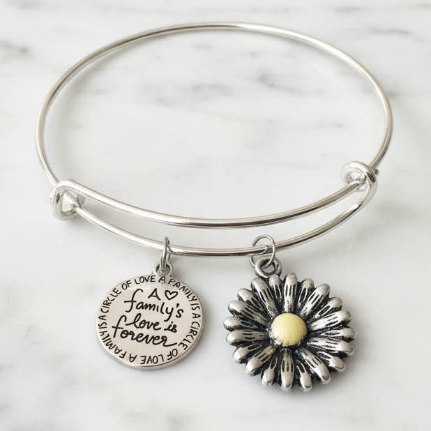 Silver adjustable bracelet with a sunflower charm and round pendant on a marble background