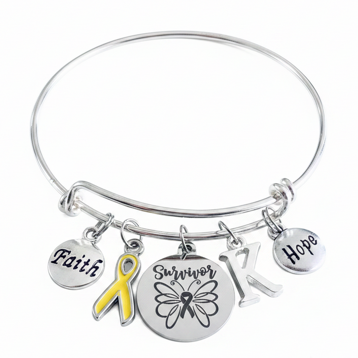 Yellow ribbon survivor bracelet with Faith disc, Survivor butterfly charm, Hope disc, and personalized initial on adjustable silver bangle — awareness jewelry gift for cancer survivors